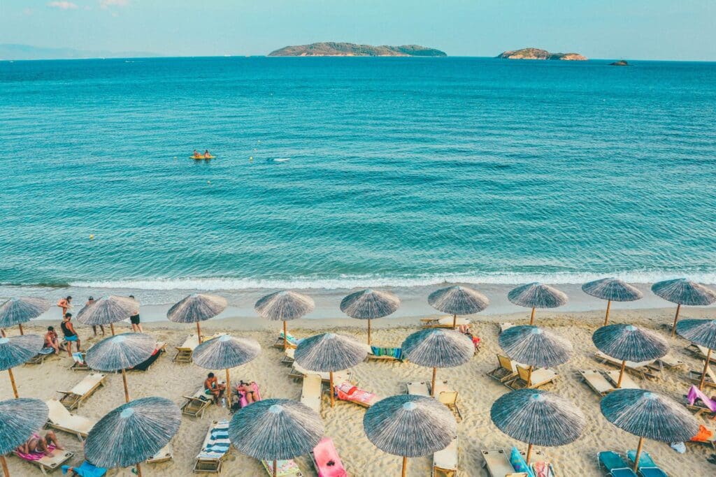 An image of a beach lined with umbrellas, for the blog post - When Traveling During Peak Season is the Best